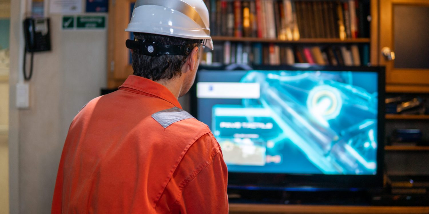 Marine chief officer wearing coverall and helmet on a ship or vessel having fun watching TV. Recreation during at sea